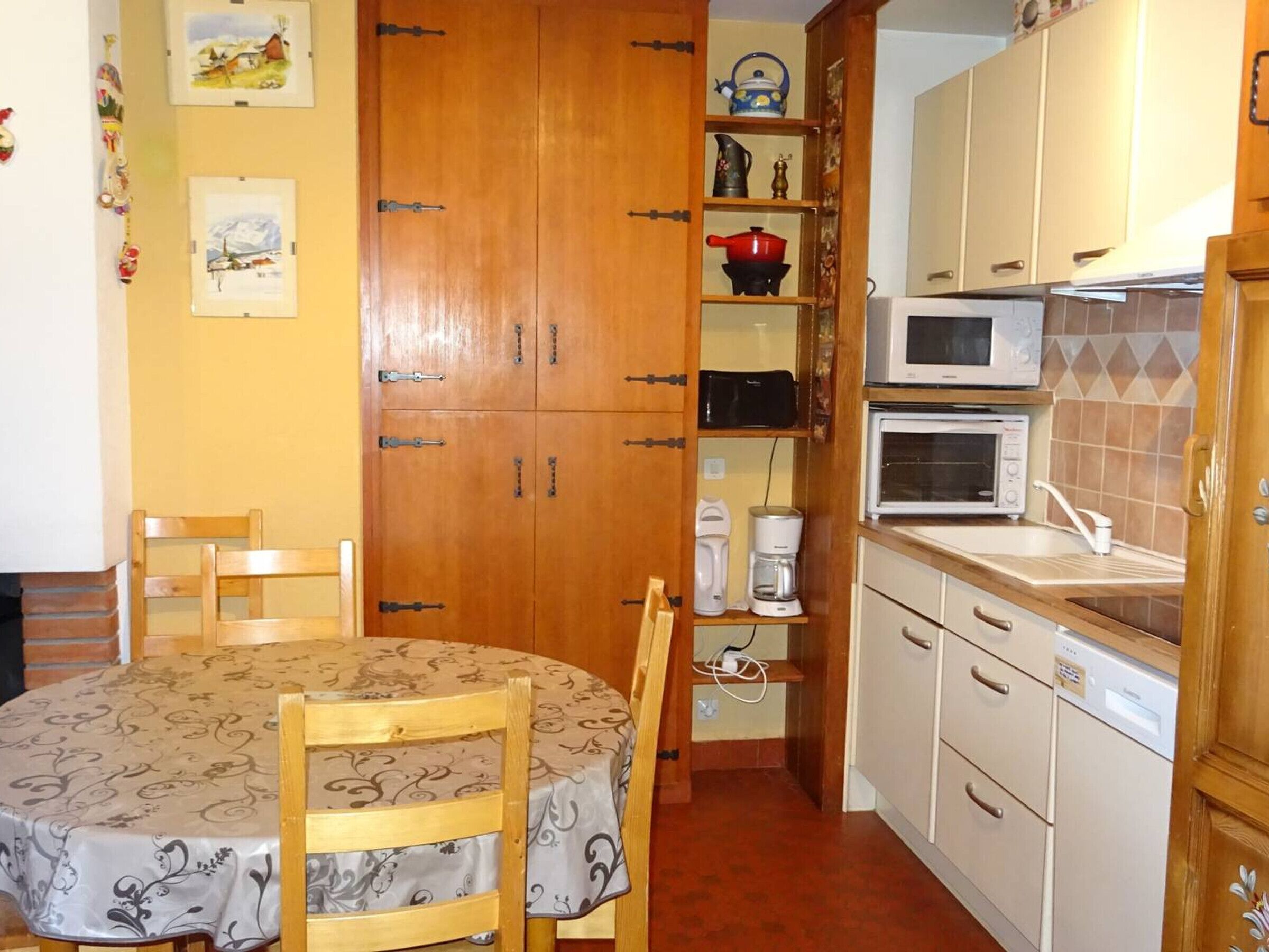 Een kleine keuken met een eettafel, stoelen en basisapparatuur.