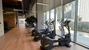 Une salle de sport moderne équipée de matériel d’exercice, dotée de grandes fenêtres et d’un plancher en bois.