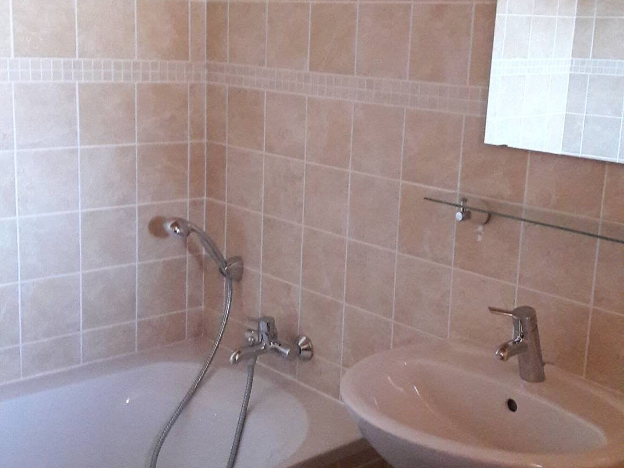 A bathroom with two sinks, one with a shower head, and a mirror above the sink.