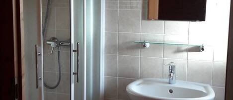 A bathroom with a glass shower enclosure, a white sink, and a mirror above the sink.
