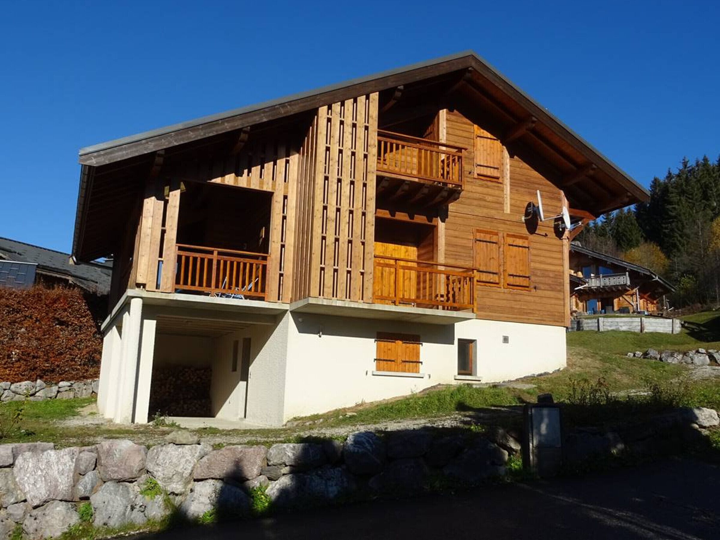 Een houten chalet met een balkon, een stenen fundering en een heldere lucht.