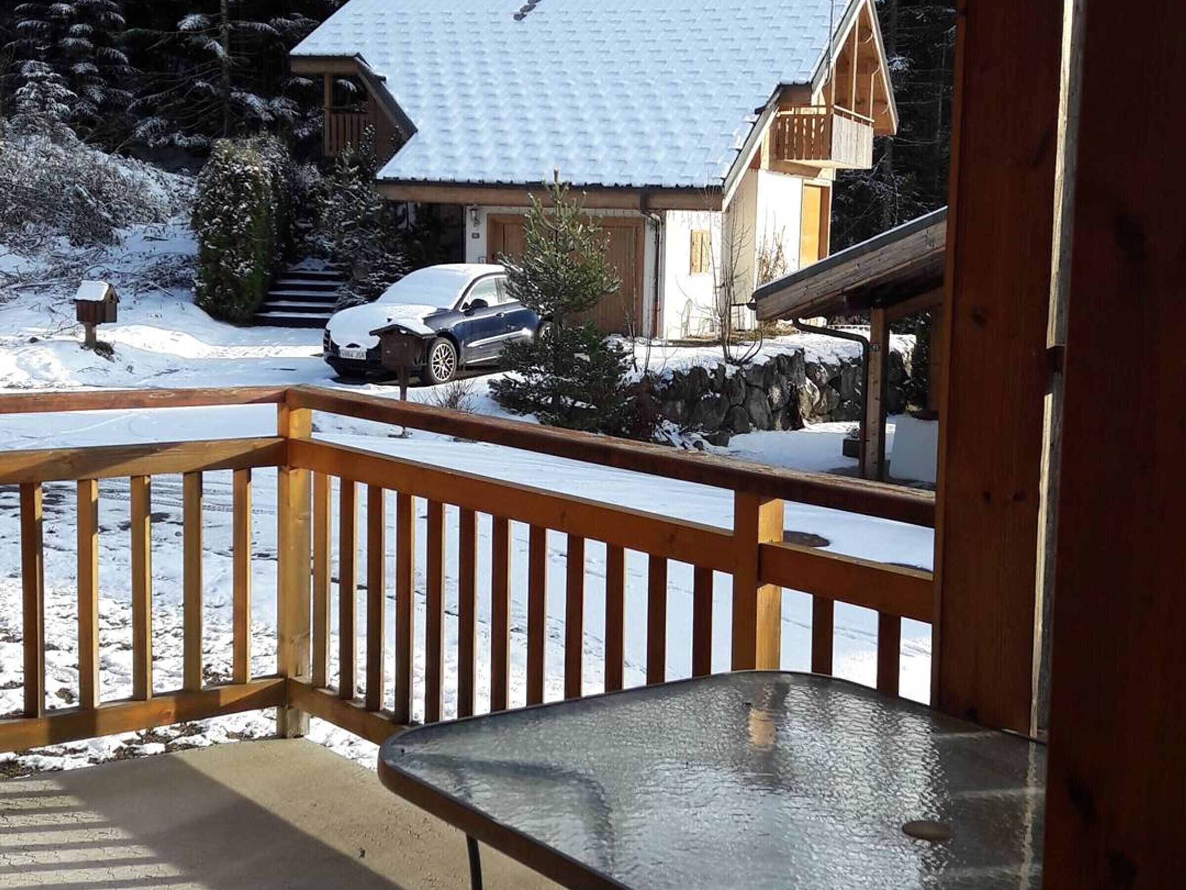 A wooden balcony with a glass table.