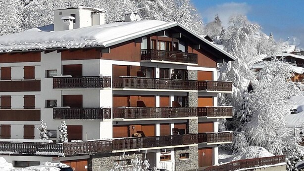 A multi-story hotel with balconies, surrounded by snow-covered trees. - Studio in Les Gets - 4 people - Central, parking, quiet (Les Gets)