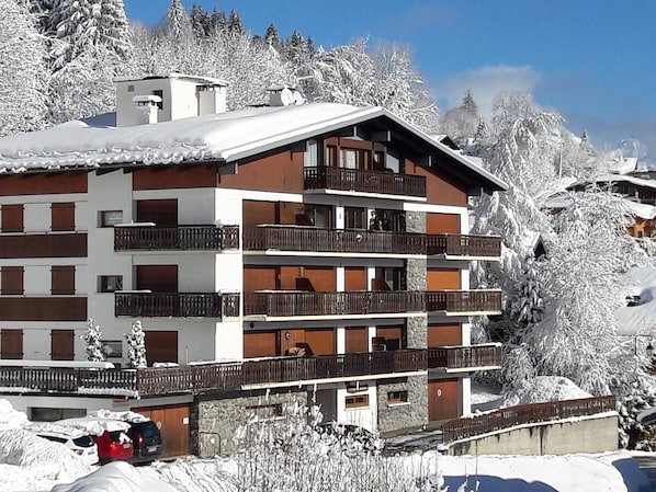 A multi-story hotel with balconies, surrounded by snow-covered trees.