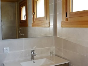 Un baño con un espejo grande, un lavabo y marcos de ventana de madera.