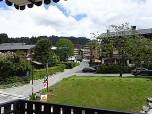 A residential street with houses, a grassy area, and a road.