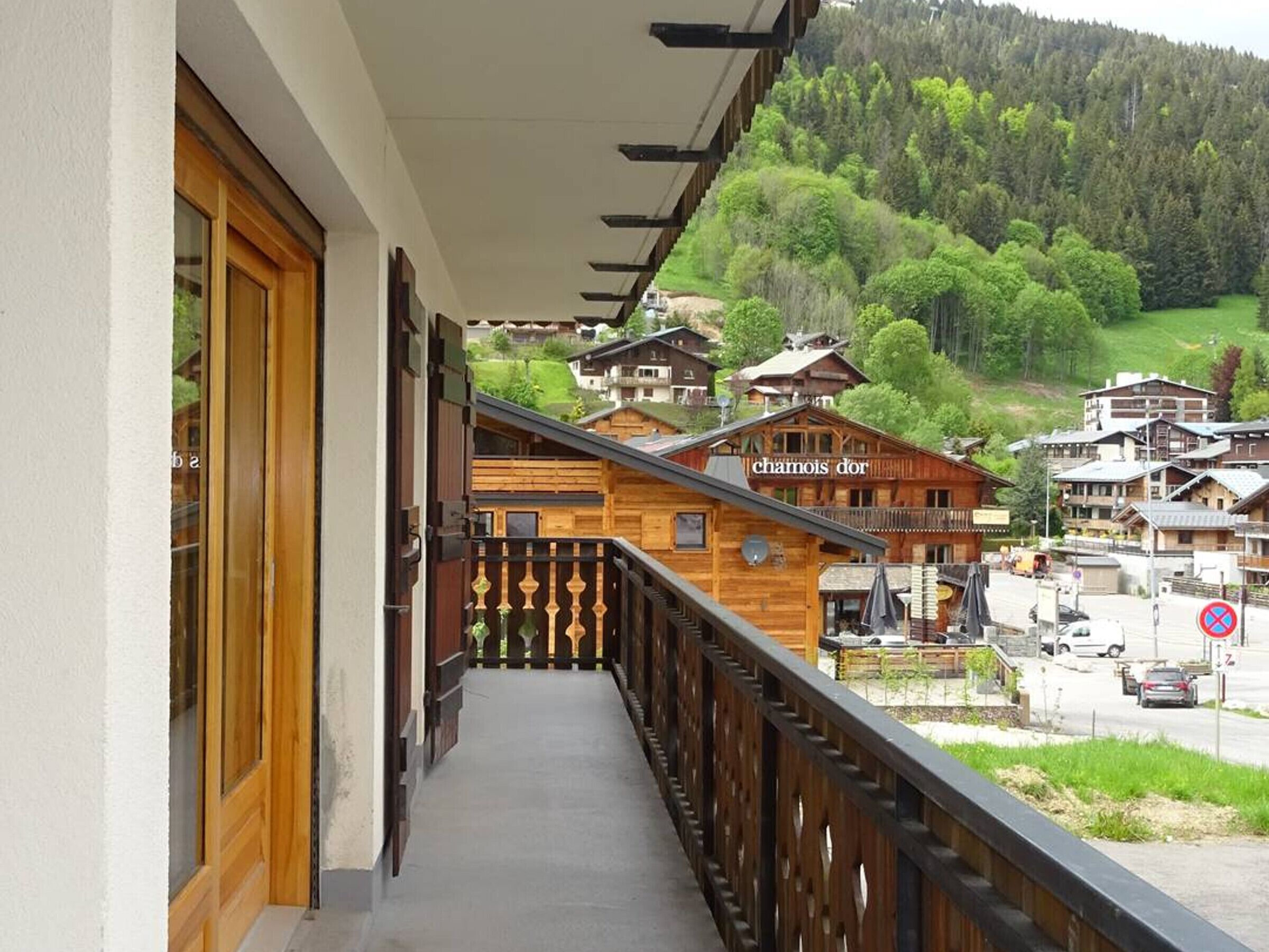 Ein hölzernes Gebäude mit Balkon, einem Schild mit der Aufschrift "chamois dor" und Blick auf einen grünen Hügel mit weiteren Gebäuden.