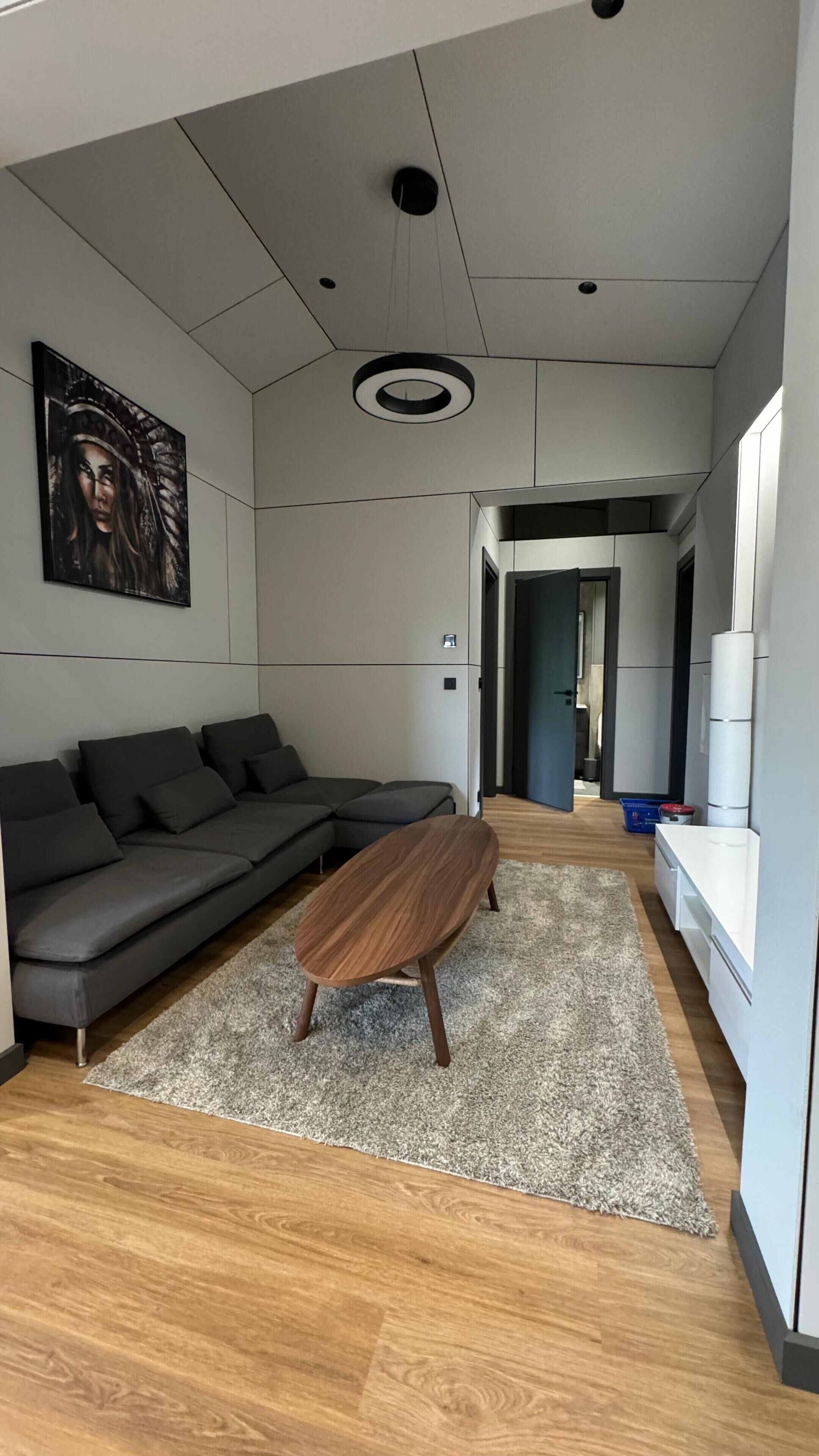A modern living room with a sectional sofa, a wooden coffee table, and a large abstract painting on the wall.