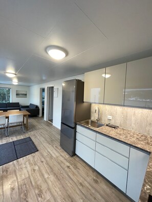 A modern kitchen with a built-in refrigerator, a sink, and a dining area with a table and chairs.