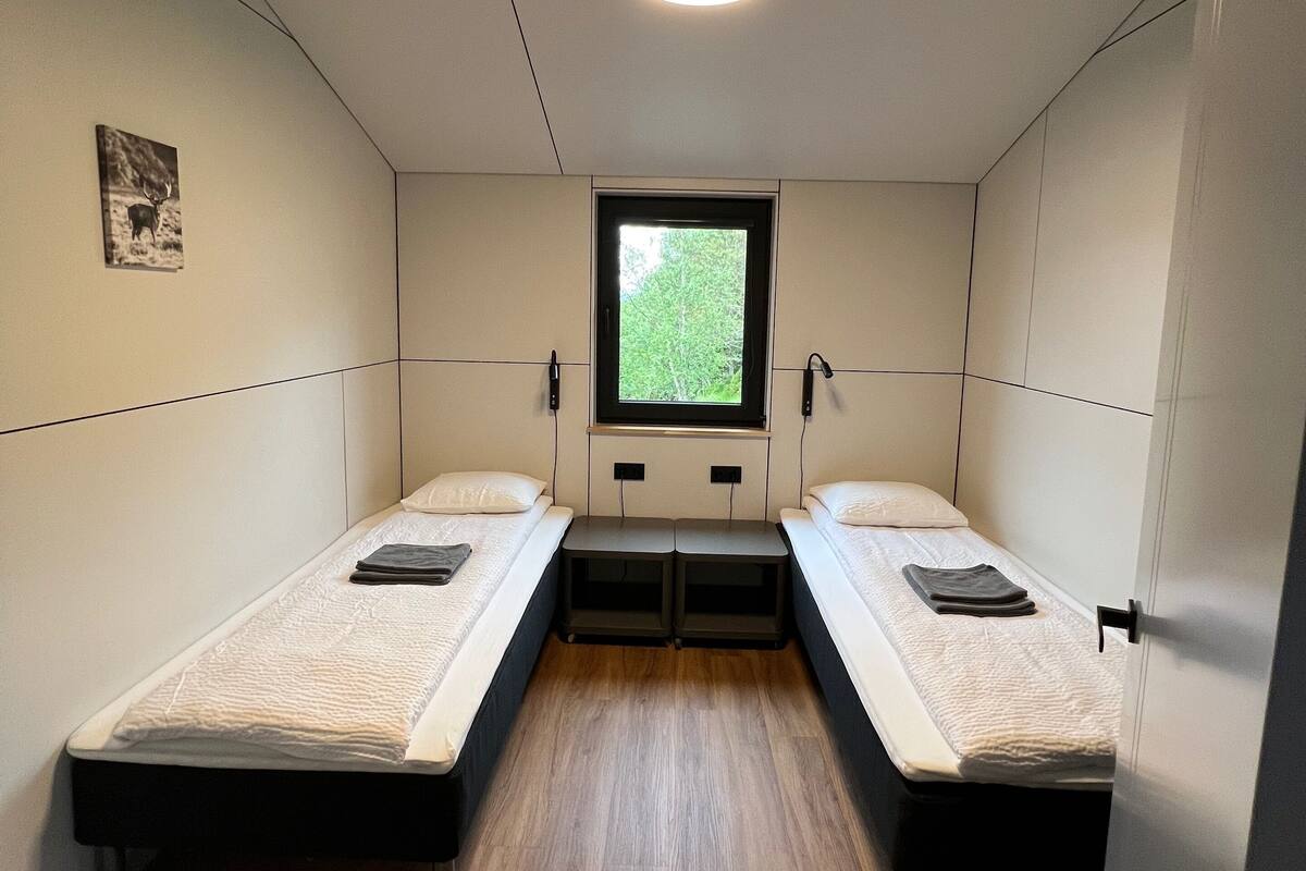 A compact room with two single beds, a small window, and a ceiling light.
