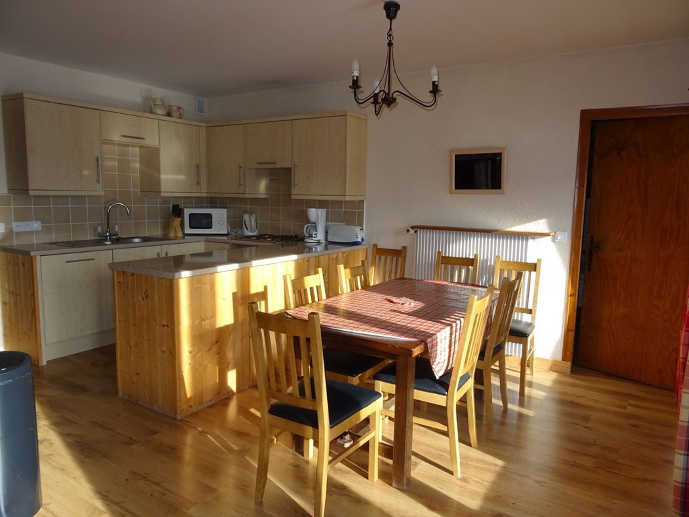 A compact kitchen with wooden cabinets, a microwave, and a dining area with a table and chairs.