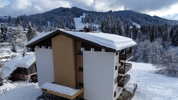 Un chalet enneigé doté d’un balcon et d’un petit espace porche.