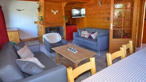 A cozy cabin interior with a sofa, a wooden table, a television, and a fireplace. - Les Gets - Duplex 5 rooms, 10 pers, near slopes, terrace, parking (Les Gets)