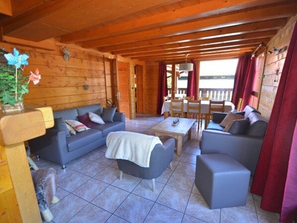 Un intérieur chaleureux, avec des boiseries, un ensemble de canapés, une table basse et un coin repas.