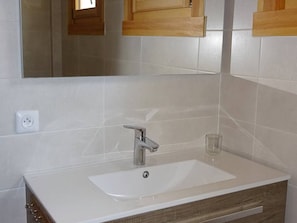 A bathroom with a white sink, a mirror, and wooden cabinets.
