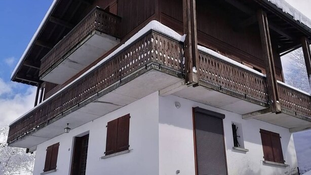 A two-story building with a wooden balcony and a snow-covered roof. - Les Gets Duplex 3-Room - 6 Pax, Comfortable, Garage (Les Gets)