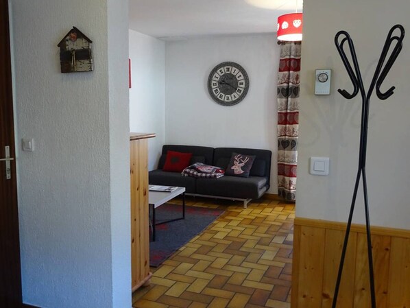 Una sala de estar con un sofá, un reloj de pared y una cortina estampada en rojo y blanco.