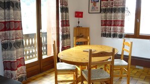 A dining area with a round wooden table and four chairs, a wooden cabinet, and a framed picture on the wall. - Les Gets Duplex 3-Room - 6 Pax, Comfortable, Garage (Les Gets)