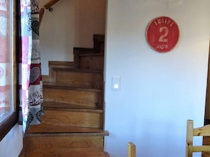Una escalera de madera que lleva a una plataforma con un letrero circular rojo en la pared.