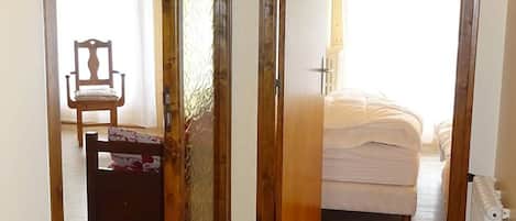 Un dormitorio con cama, una silla y un radiador.