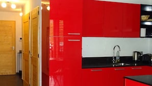 Une cuisine avec des armoires rouges, un plan de travail noir et un évier en acier inoxydable.