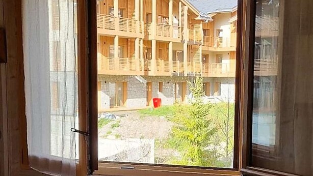 Une pièce dotée d’une grande fenêtre donnant sur un bâtiment en bois agrémenté de balcons.