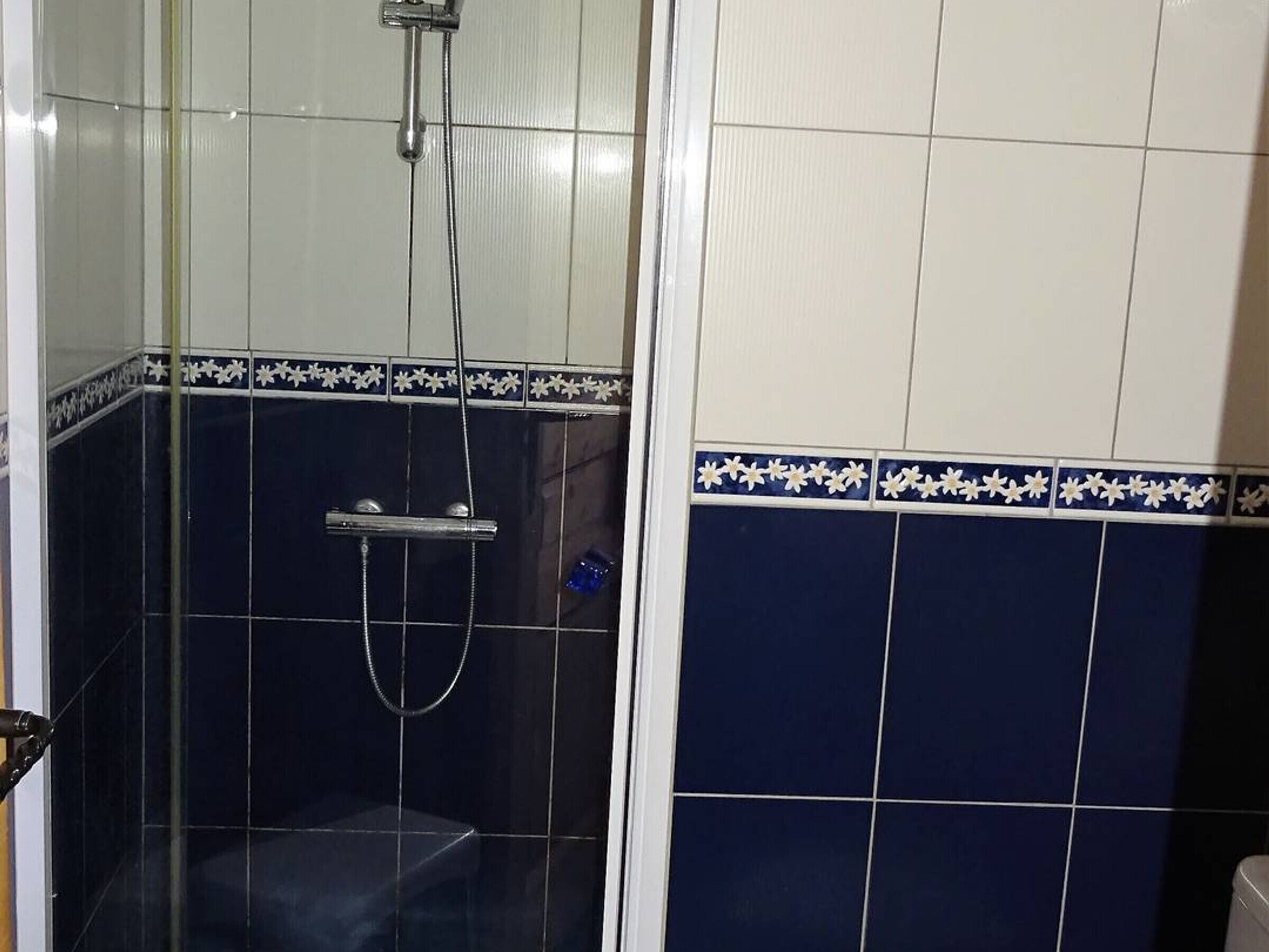 A bathroom with a shower area, tiled walls, and a toilet.