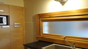 A compact kitchen with a microwave, a sink, and wooden cabinets. - Spacious 2-BR Apartment for 7 with WiFi, Central Heating, and Parking - Les Gets (Les Gets)