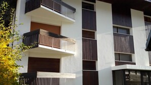 Un edificio moderno con varios balcones, grandes ventanales y una combinación de paneles blancos y oscuros.