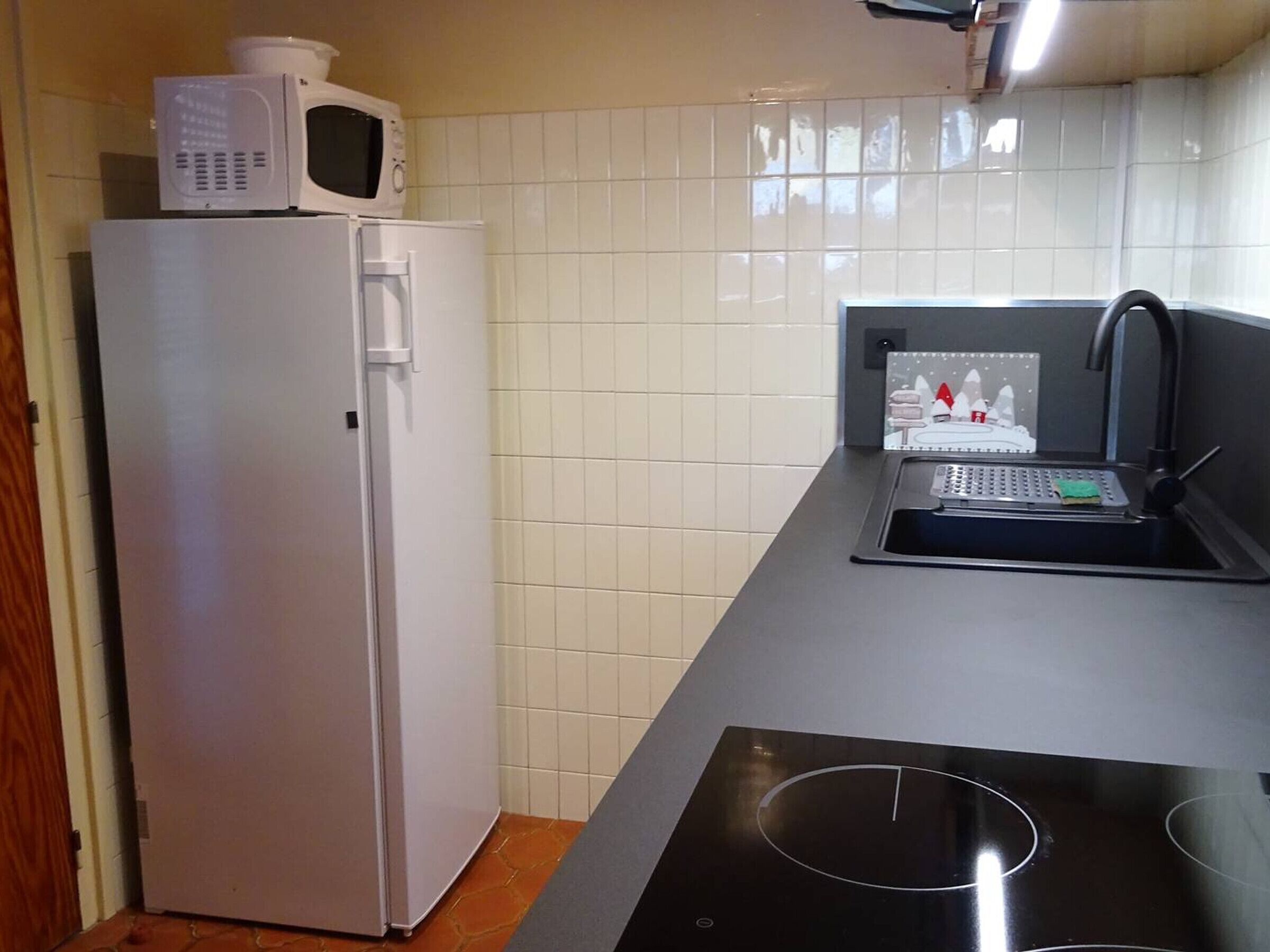 Una cucina compatta con frigorifero bianco, forno a microonde, lavello e fornelli.