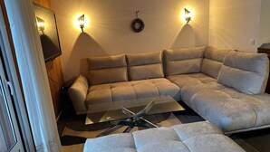 A living room with a sectional sofa, a glass coffee table, and two wall-mounted lamps. - Spacious 6-Room Duplex, 12 Guests, WiFi, Garage, Close to Slopes - Sheets & Towels Included in Winter (Les Gets)