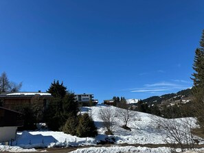 A snow-covered landscape with buildings, trees, and a clear blue sky.