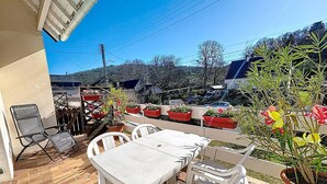 Eine Außenpatio mit weißen Tischen und Stühlen, Blumentöpfen und Blick auf die Umgebung.