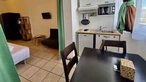 Une chambre d’hôtel compacte comprenant un coin cuisine, un lit, une petite table et un téléviseur.