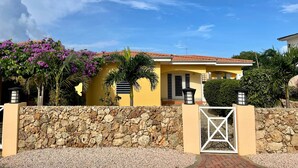 A yellow building with a stone wall and a gate.
