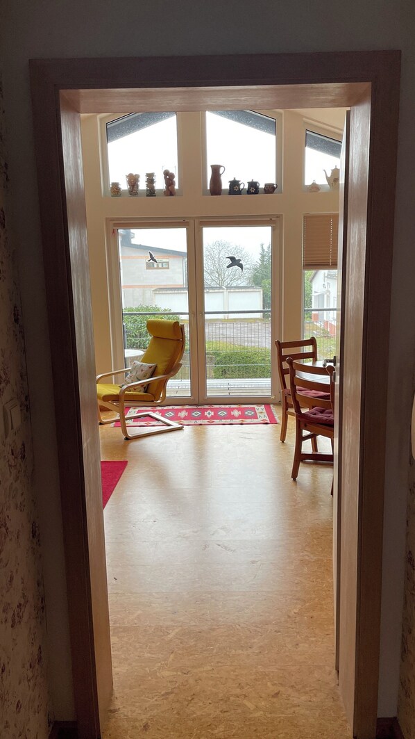 Una habitación con piso de madera, una silla amarilla, una mesa de madera y vistas a un espacio exterior con una silla amarilla y una mesa.