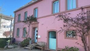 A pink building with multiple windows and a door, a small bench, and some potted plants. - The Blue House - from hay barn to vacation apartment - now with SAUNA (Pirmasens)