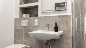 Une salle de bain moderne avec un lavabo blanc, des toilettes et un espace douche.