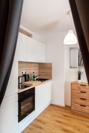 A modern kitchen with white cabinets, a wooden countertop, a built-in oven, and a hanging pendant light. - Accessible Vacation Apartment in Dresden Neustadt—Your Stylish Temporary Home (Dresden)
