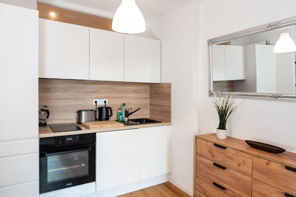 A modern kitchen with white cabinets, a wooden countertop, a built-in oven, a sink, and a mirror above the counter. - Accessible Vacation Apartment in Dresden Neustadt—Your Stylish Temporary Home (Dresden)