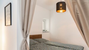 Une chambre à coucher avec un lit, des rideaux, un luminaire suspendu, un miroir et un tableau encadré accroché au mur.
