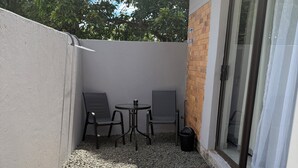 A small patio area with a table and two chairs, a gravel path, and a door leading to a covered area. - Charming B&B with WiFi and AC in Welkom, South Africa (Welkom)