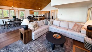 Ein modernes Wohnzimmer mit einem Ecksofa, einem runden Couchtisch und einem Essbereich mit Tisch und Stühlen.