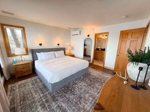 Une chambre à coucher comprenant un lit, des tables de chevet, une commode, un miroir, une armoire et une plante en pot.