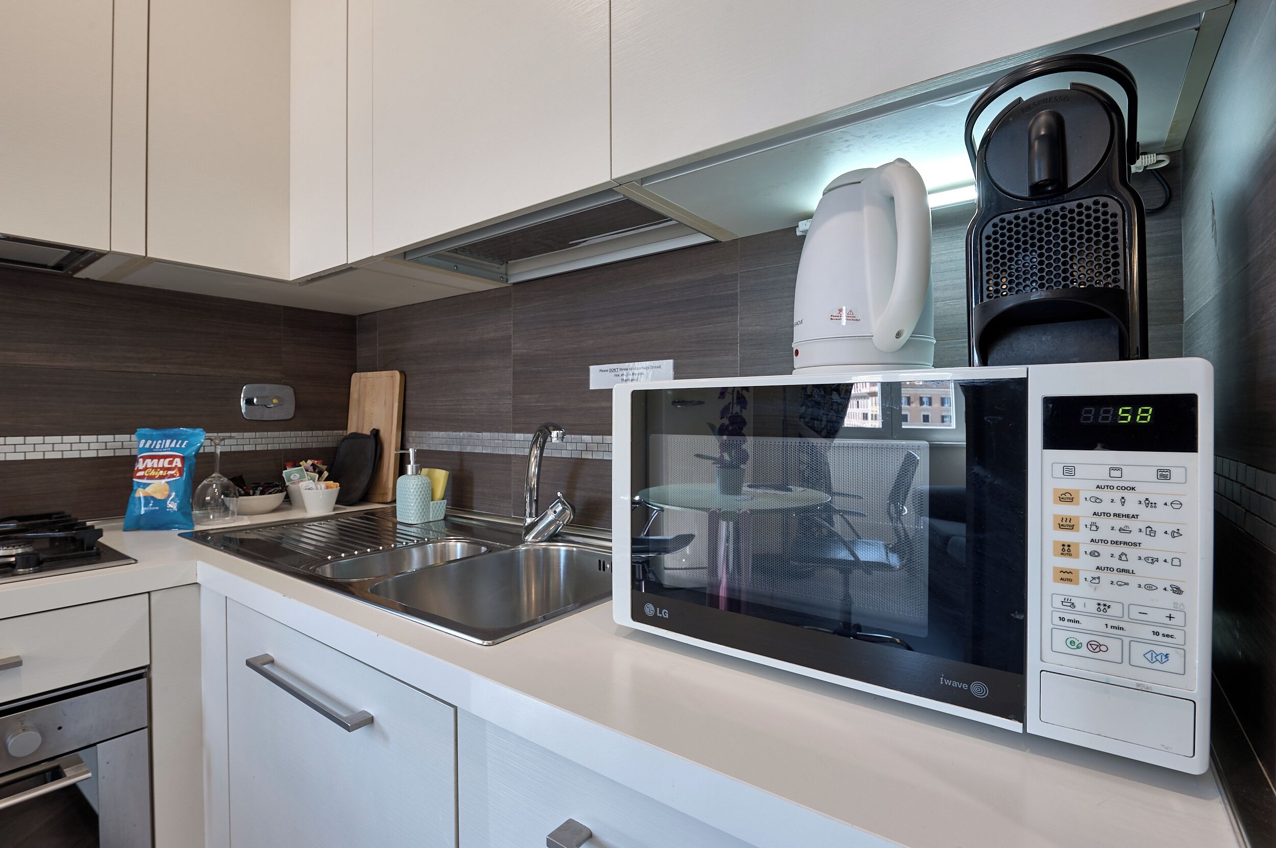 A modern kitchen with a built-in microwave, kettle, and coffee maker.