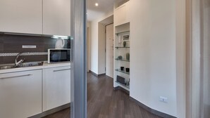 A modern kitchen with white cabinets, a stainless steel sink, a microwave, and a glass shelf with decorative items. - A casa Di Roberta  (Rome)
