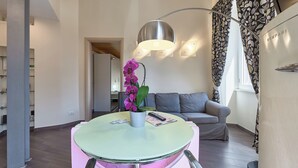 A modern living room with a round table, a potted orchid, a grey sofa, and a staircase with patterned curtains. - A casa Di Roberta  (Rome)