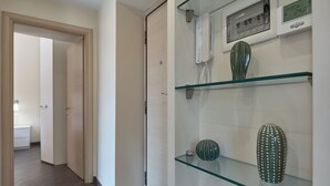 A hallway with a glass shelf displaying a cactus, a vase, and a telephone. - A casa Di Roberta  (Rome)