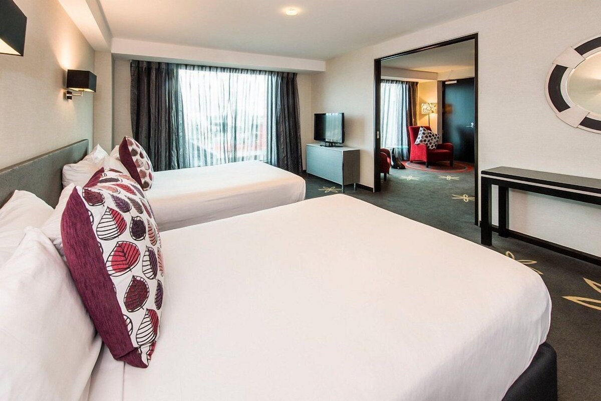 Une chambre d’hôtel avec deux lits, une télévision, un bureau et un miroir.