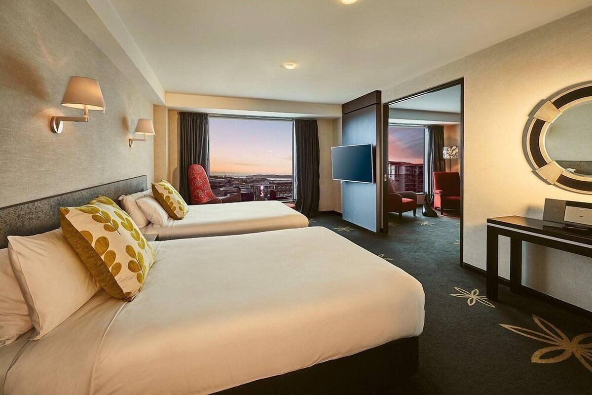 Una habitación de hotel con dos camas, televisión, escritorio y vistas a la ciudad.